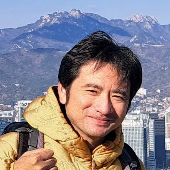代表者の坂本 祥太朗。山と街並みを背に、ほほえむ写真